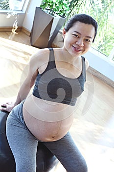 Smiling pregnant woman sitting on yoga ball