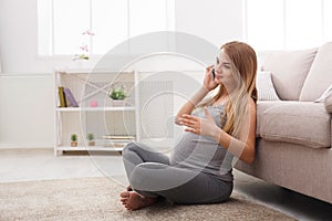 Smiling pregnant woman talking on her smartphone