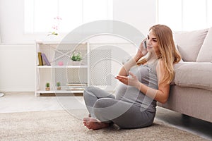 Smiling pregnant woman talking on her smartphone