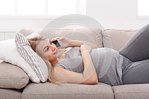 Smiling pregnant woman talking on her smartphone