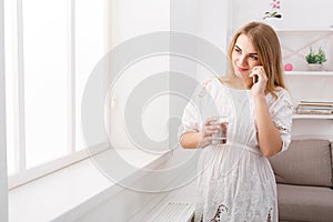 Smiling pregnant woman talking on her smartphone, copy space.