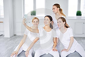 Smiling Pregnant Women Sitting On Fitballs Taking Photo On Smartphone, Posing