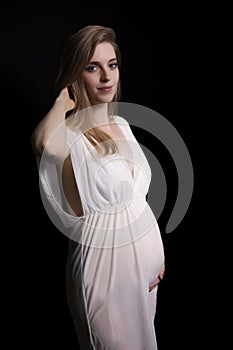 Smiling pregnant young woman is posing on black background
