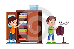 Smiling preschool boys kids taking clothes out of closet shelf and hanging suit jacket on floor hanger stand