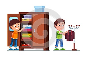 Smiling preschool boys kids taking clothes out of closet shelf and hanging suit jacket on floor hanger stand photo