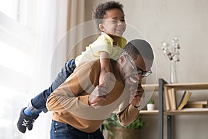 Smiling preschooler boy piggyback playing with dad