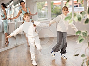 Smiling preteen girl practicing vigorous dance with boy in choreography studio