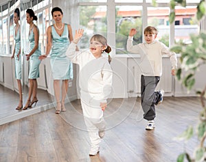 Smiling preteen girl practicing vigorous dance with boy in choreography studio