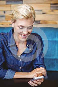 Smiling pretty blonde sending a text message