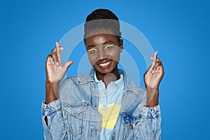 Smiling pretty bright young african woman with fingers crossed