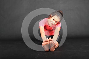 Smiling girl exercising yoga - seated forward fold