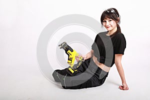 Smiling pretty girl in working clothes with hand held electric saw