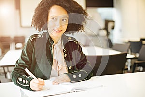 Smiling pretty latin student girl sitting in class room