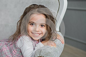 Smiling pretty little girl on a grey sofa