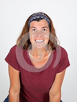 Smiling pretty middle aged brunette woman looking at camera while standing against white background