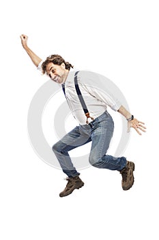 A smiling pretty redhead man with a beard in jeans and a white shirt is jumping. Isolated over white background.