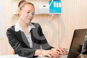 Smiling pretty secretary typing text on computer