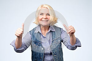 Smiling pretty senior woman showing thumbs up