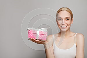 Smiling pretty woman holding pink gift box present on white background