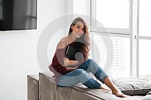 Smiling pretty woman in sweater holding tablet computer