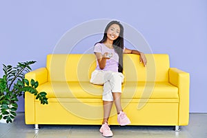 Smiling pretty woman watch tv holding remote control sitting on sofa