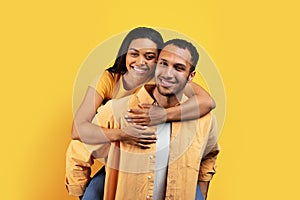 Smiling pretty young african american man hold woman on back, have fun in free time, enjoy game