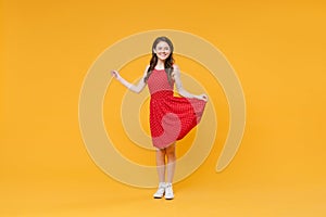 Smiling pretty young brunette woman girl in red summer dress posing isolated on yellow wall background studio portrait