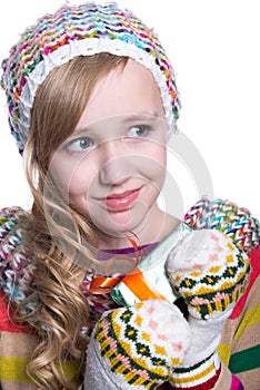 Smiling pretty young girl wearing coloful knitted scarf, hat and mittens, holding christmas gift isolated on white background.