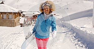 Smiling pretty young woman carrying a snowboard