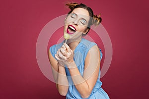 Smiling pretty young woman holding lollipop and singing