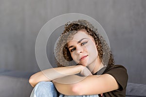 Smiling young woman wearing casual clothes relaxing on a couch at home