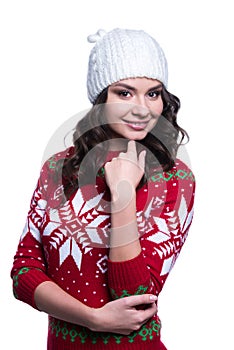 Smiling pretty young woman wearing colorful knitted sweater with christmas ornament and hat. Isolated on white background.