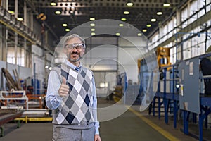 Smiling Production Manager Standing In Factory Hall And Giving Thumb Up