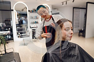 Smiling professional beauty master combing wet hair of a client in a beauty salon