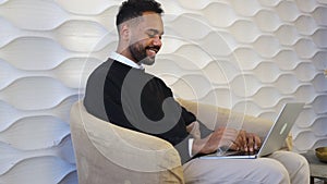 Smiling professional black african business man using laptop working from home office