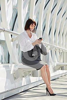 Smiling professional business woman waiting with smart phone