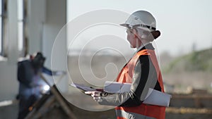 Smiling professional female heavy industry engineer in a helmet background of a construction site in hangar where