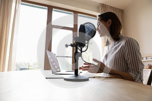 Smiling professional female radio host talking in stand microphone.