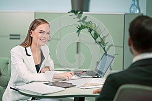 Smiling professional HR agent making a job interview to a applicant in the bright modern office. Young woman