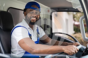 Smiling professional man mover worker in blue uniform driving truck to delivery and moving house service