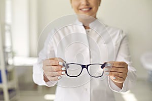 Smiling professional optician willing to help and asking you to try on new glasses