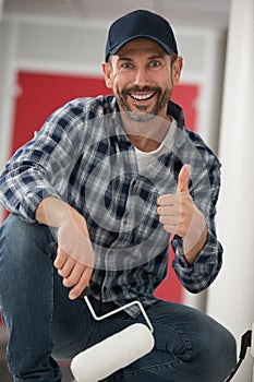 smiling professional painter in dungarees giving thumbs up