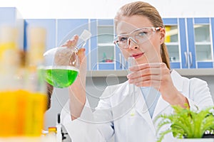 Smiling professional scientist in protective glasses making experiment