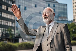 Smiling professional waving while hailing for taxi cab in the city against buildings