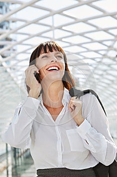 Smiling professional woman talking on smart phone in station