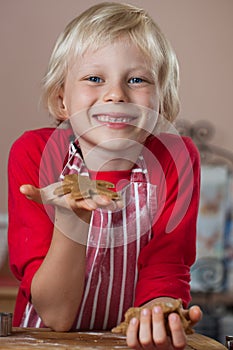 Smiling proud boy holding up gingerbread man