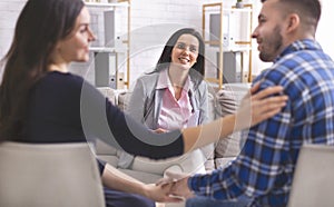 Smiling psychologist looking at lovely couple at therapy