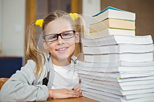 Smiling pupil next to stack of books on her desk