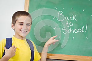 Smiling pupil pointing on back to school sign on chalkboard