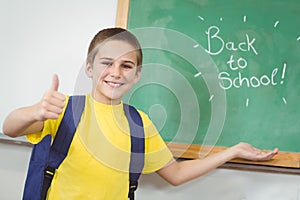 Smiling pupil showing back to school sign on chalkboard